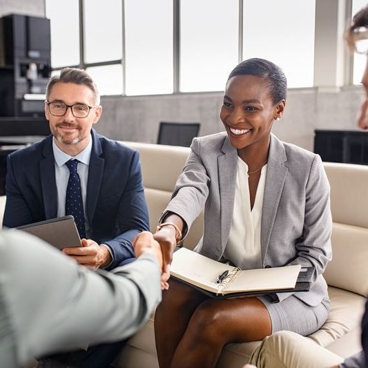 Smiling mature black businesswoman shaking hand with new client in modern office. Successful african american woman manager shaking hands with executive during business meeting. Professional ceo signing a deal with handshake with new partner.